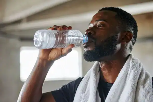 Image of man drinking water to improve hydration Billingshurst after work out.